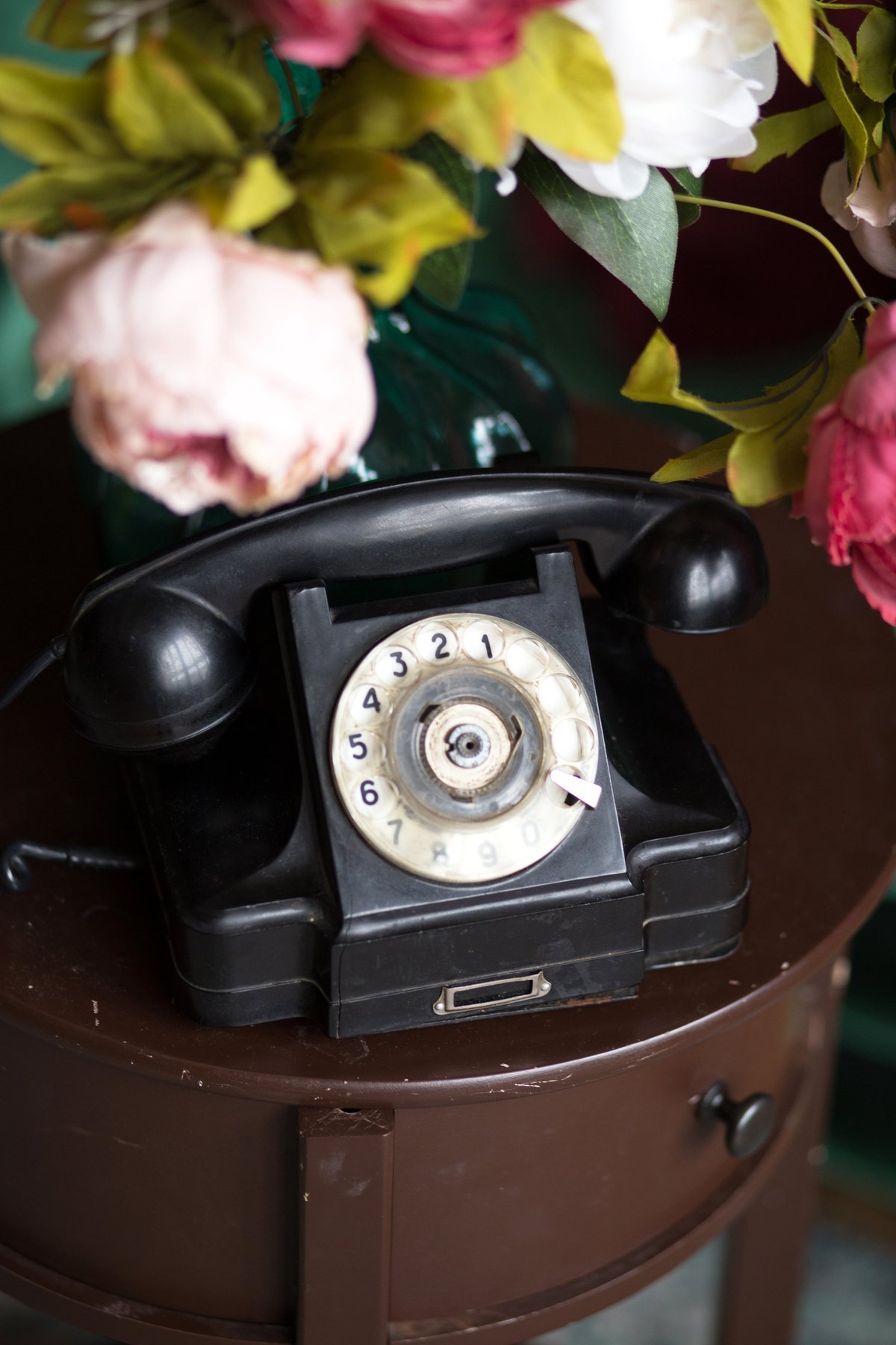 Classic rotary phone on wooden table with flowers